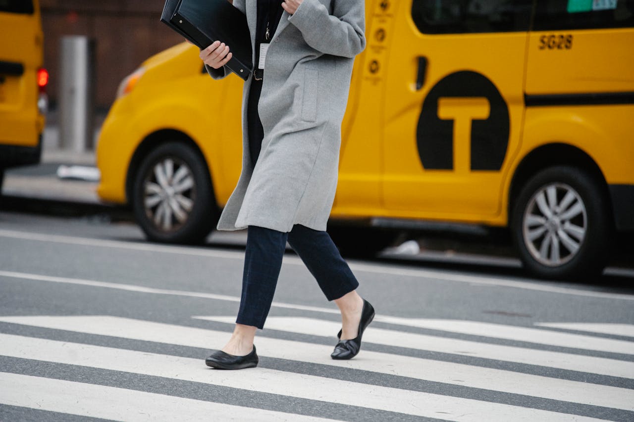 Side view crop female in formal clothes carrying documents folders crossing busy road in urban city district